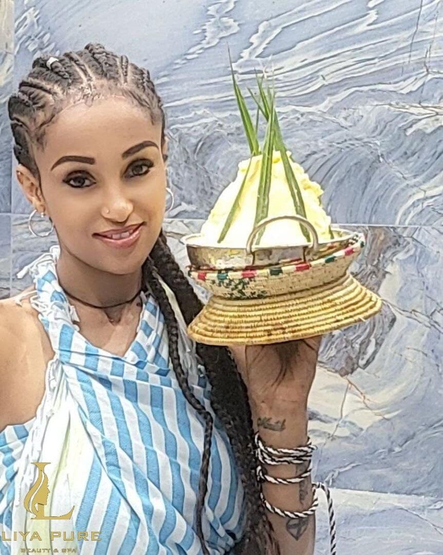 Guest with braided hair holding a traditional hair butter bowl at Liya